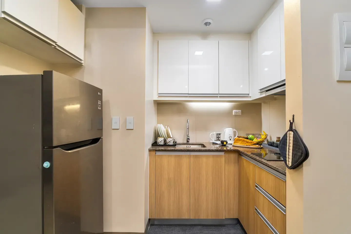 A kitchen with a refrigerator , sink , and cabinets.  The Den at Bayshore Luxe by Prime, Manila