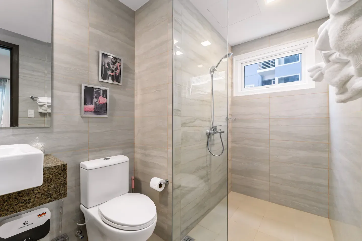 A bathroom with a toilet , sink , shower and mirror. Bayshore Luxe by Prime, Manila
