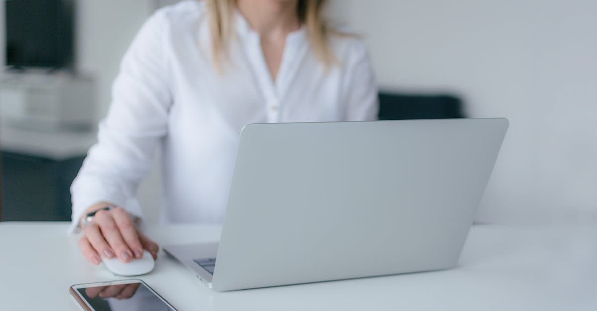 A woman is sitting at a table using a laptop computer.