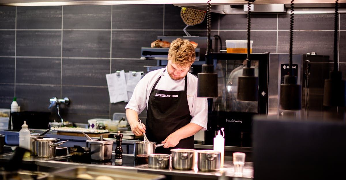 A man in an apron is cooking in a restaurant kitchen.