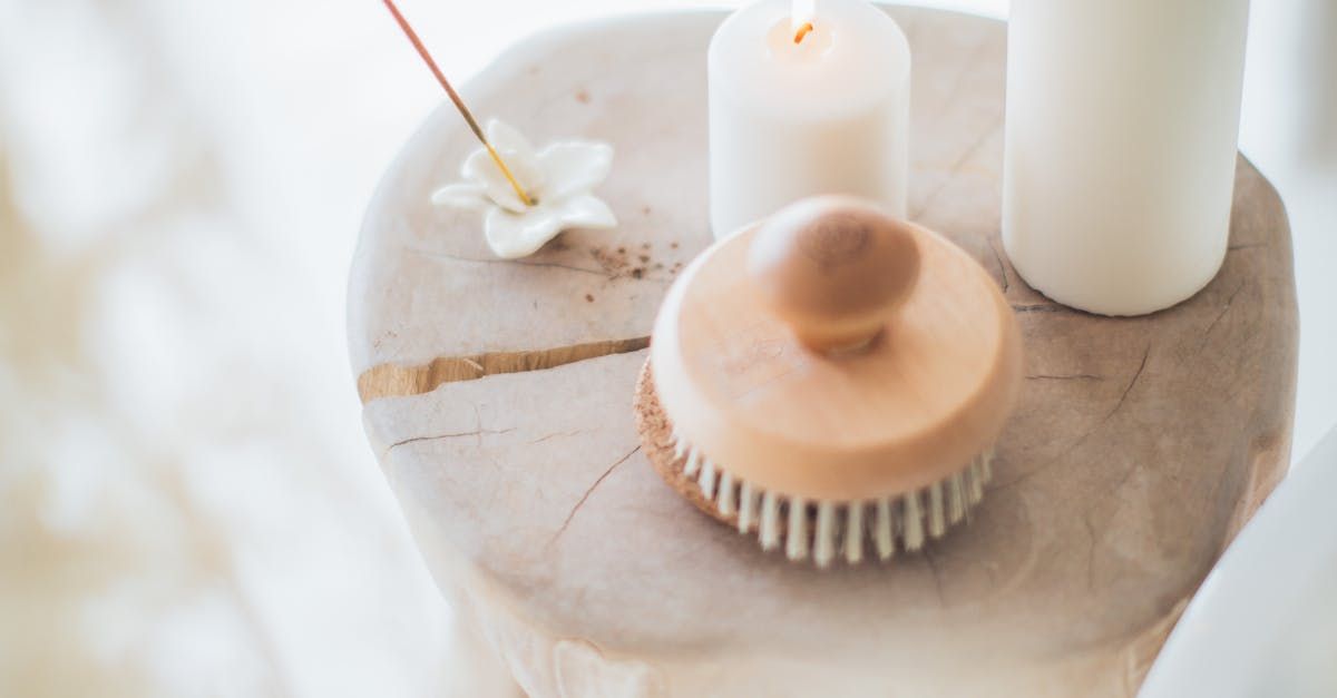 A wooden brush is sitting on a wooden table next to candles and incense sticks.