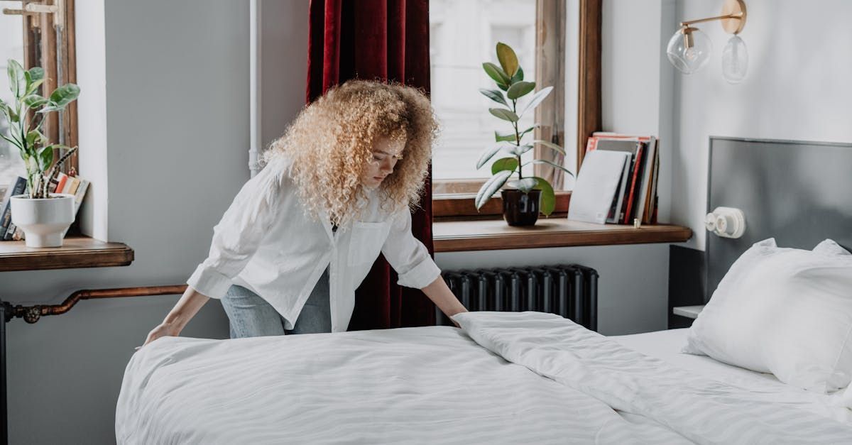 A woman is making a bed in a bedroom.