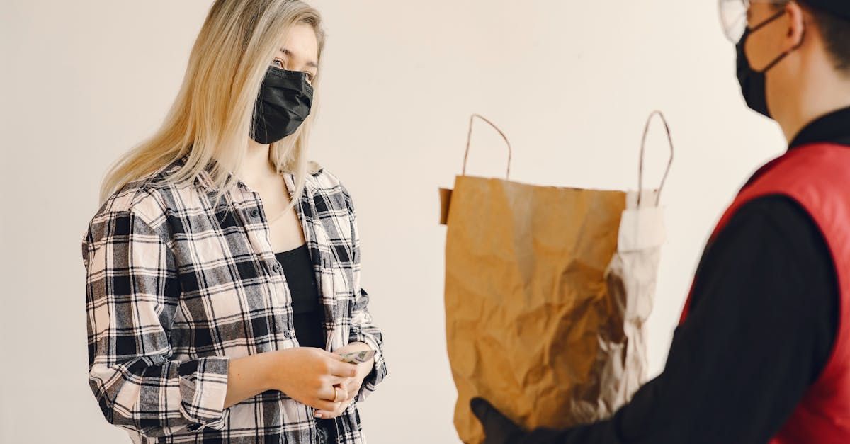 A woman wearing a mask is getting a bag of food from a delivery man.