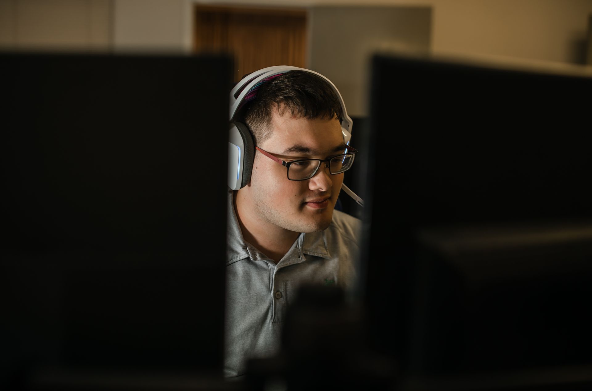 A man wearing headphones and glasses is sitting in front of a computer monitor.
