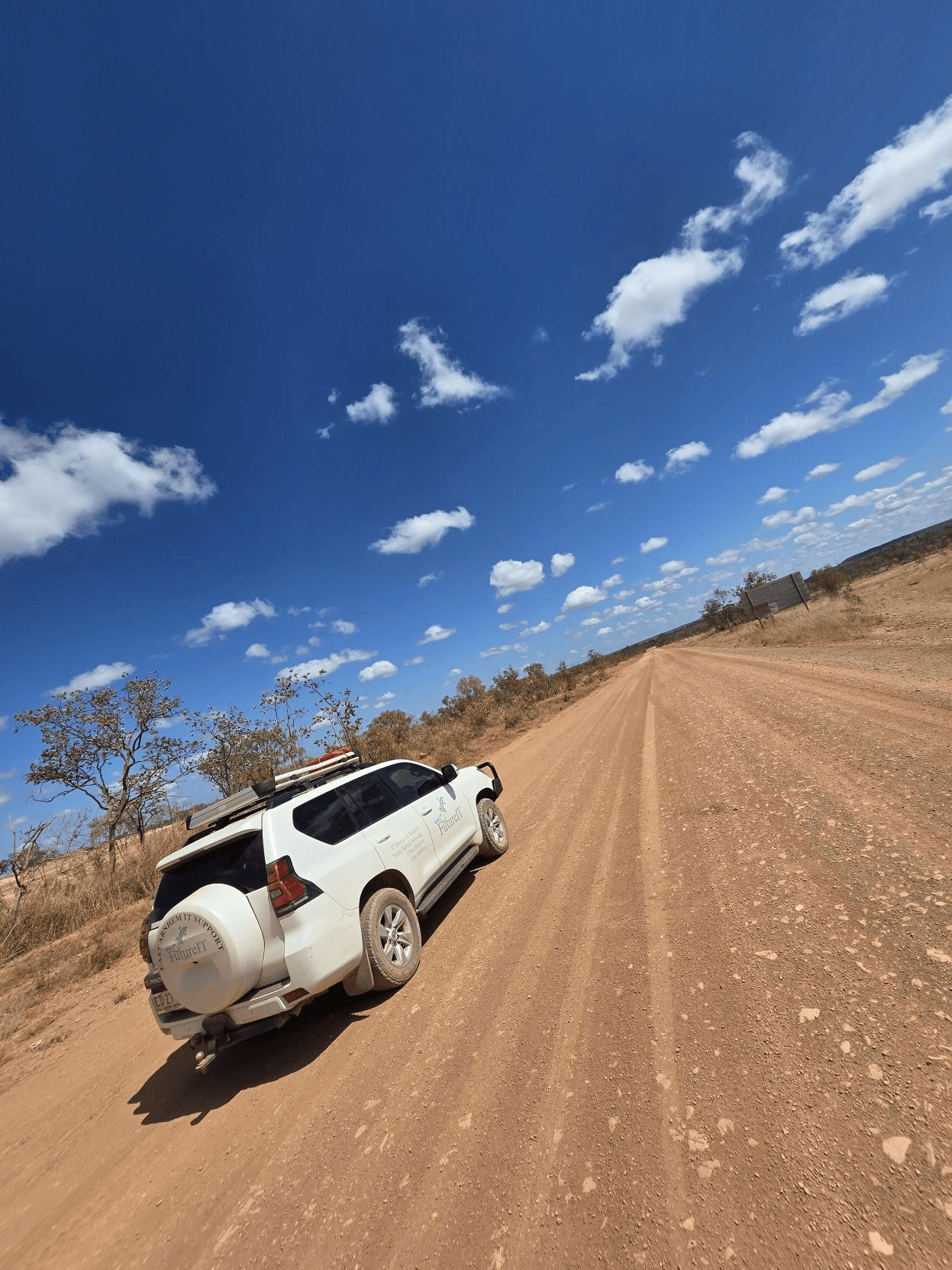 A white suv is driving down a dirt road.