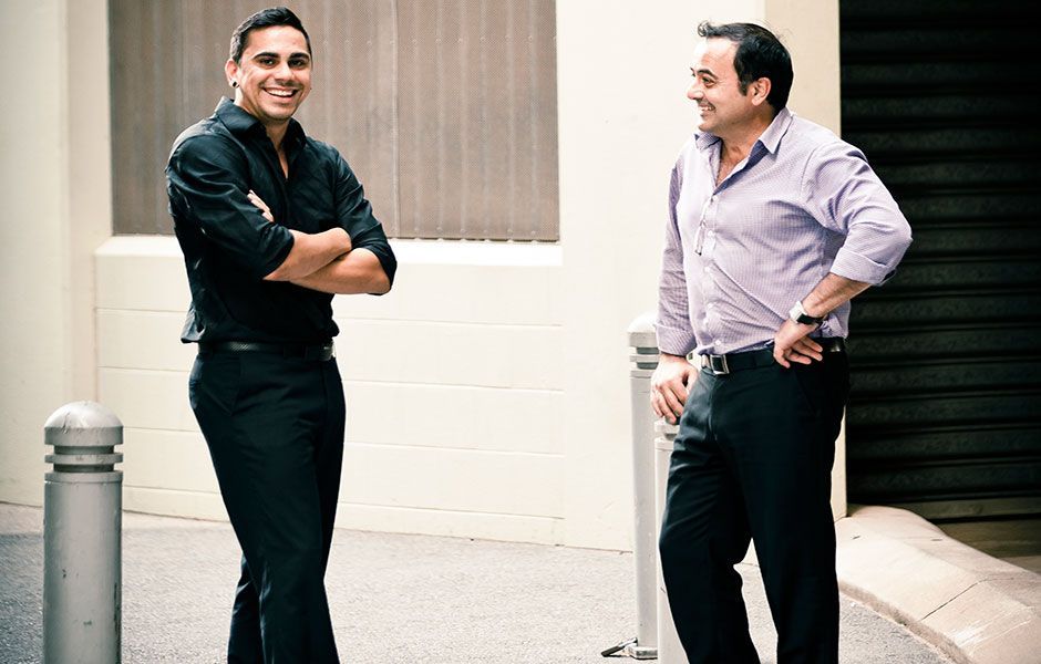 Two men standing next to each other with their arms crossed