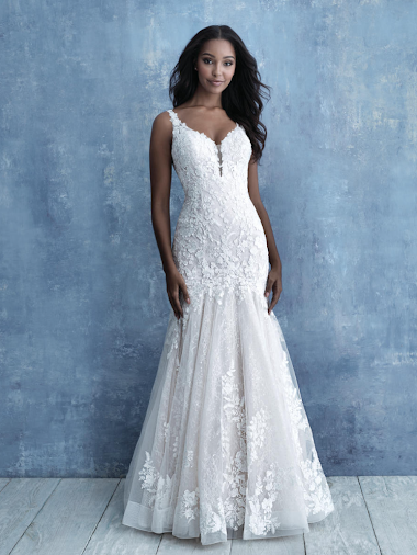 Woman in a white mermaid wedding dress stands on a beach.