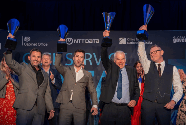 A group of people celebrating and hold a trophy from the Civil Service Data Challenge 2024. Projection Constellation celebrate winning Civil Service AI & Data Challenge 2024. 