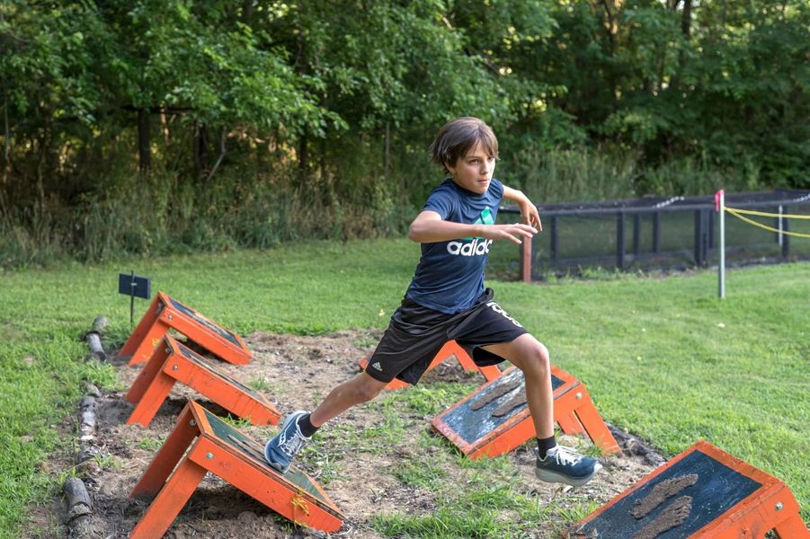 Runner leaping over orange hurdles on a grassy outdoor course