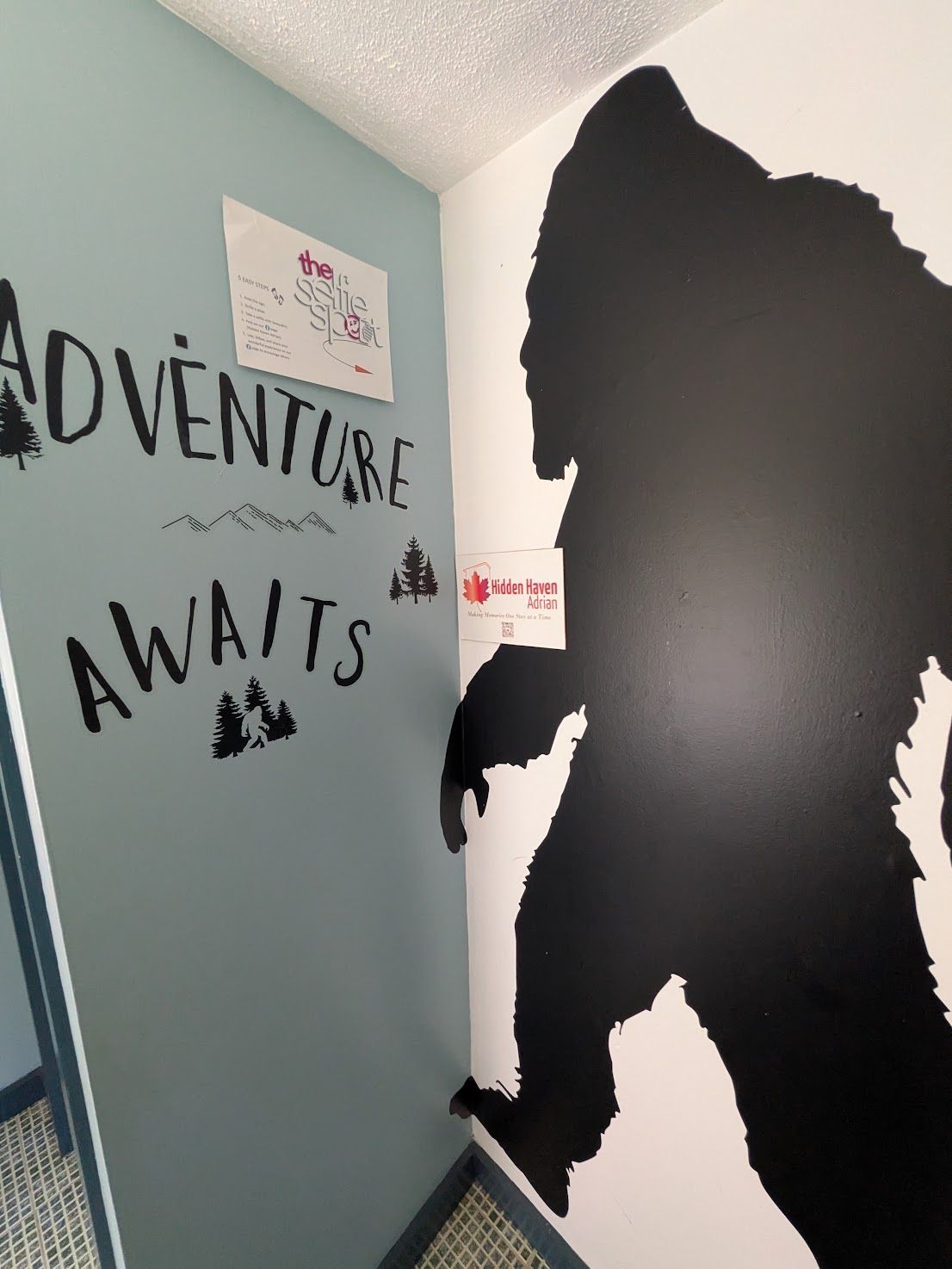 Hallway wall with “Adventure Awaits” text and a large black silhouette mural on a light blue wall