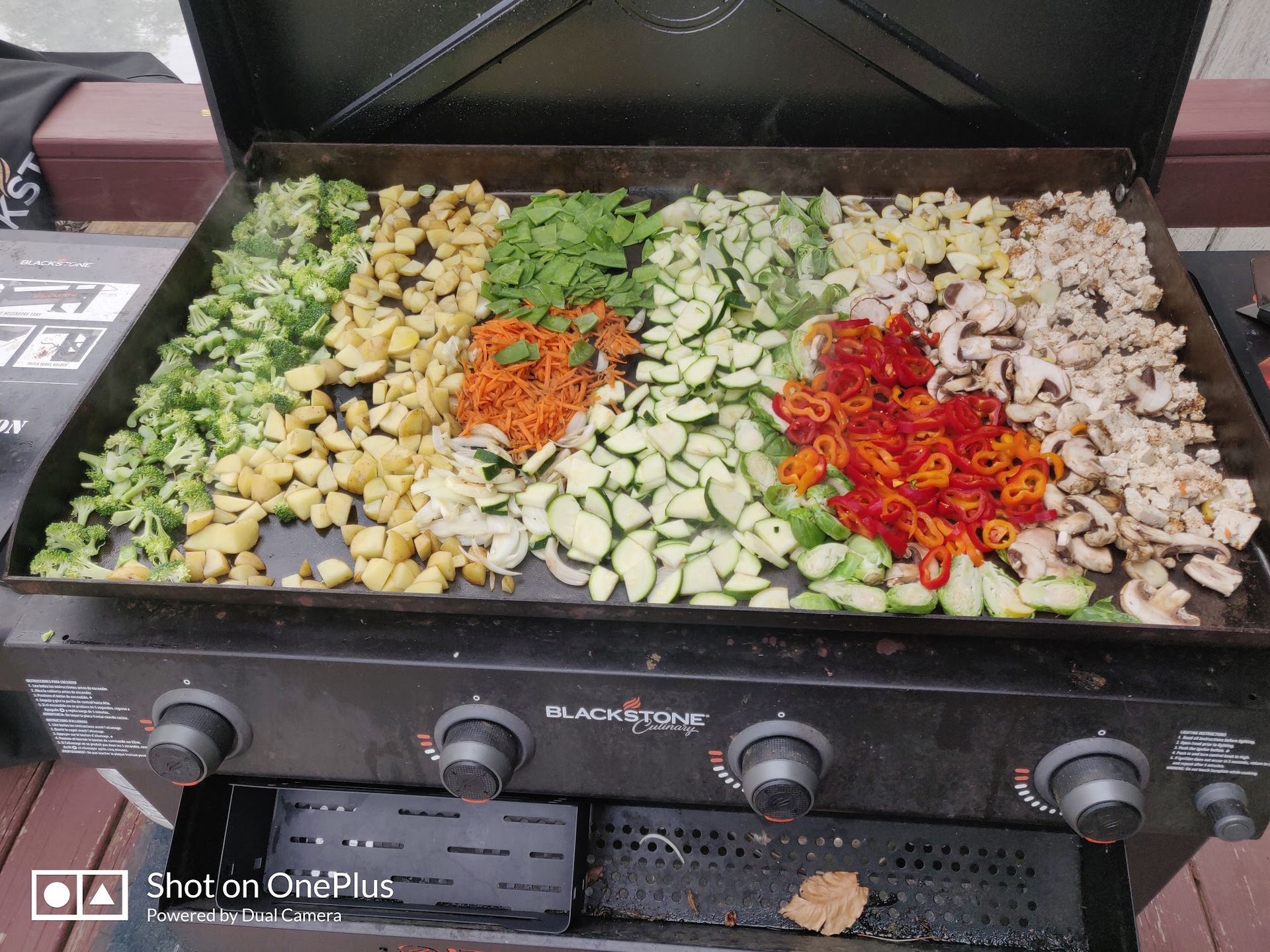Four sections of chopped vegetables cooking on a black grill griddle