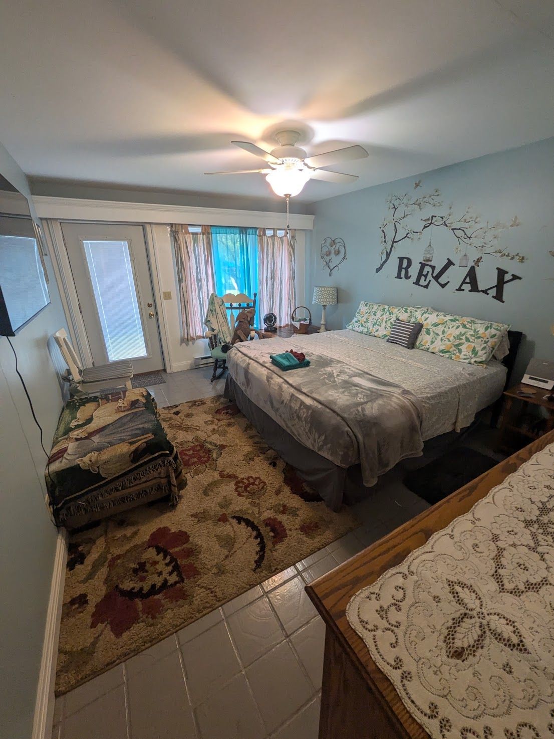 Bedroom with a bed, dresser, rug, and mirrored closet doors in a bright, neutral-toned room