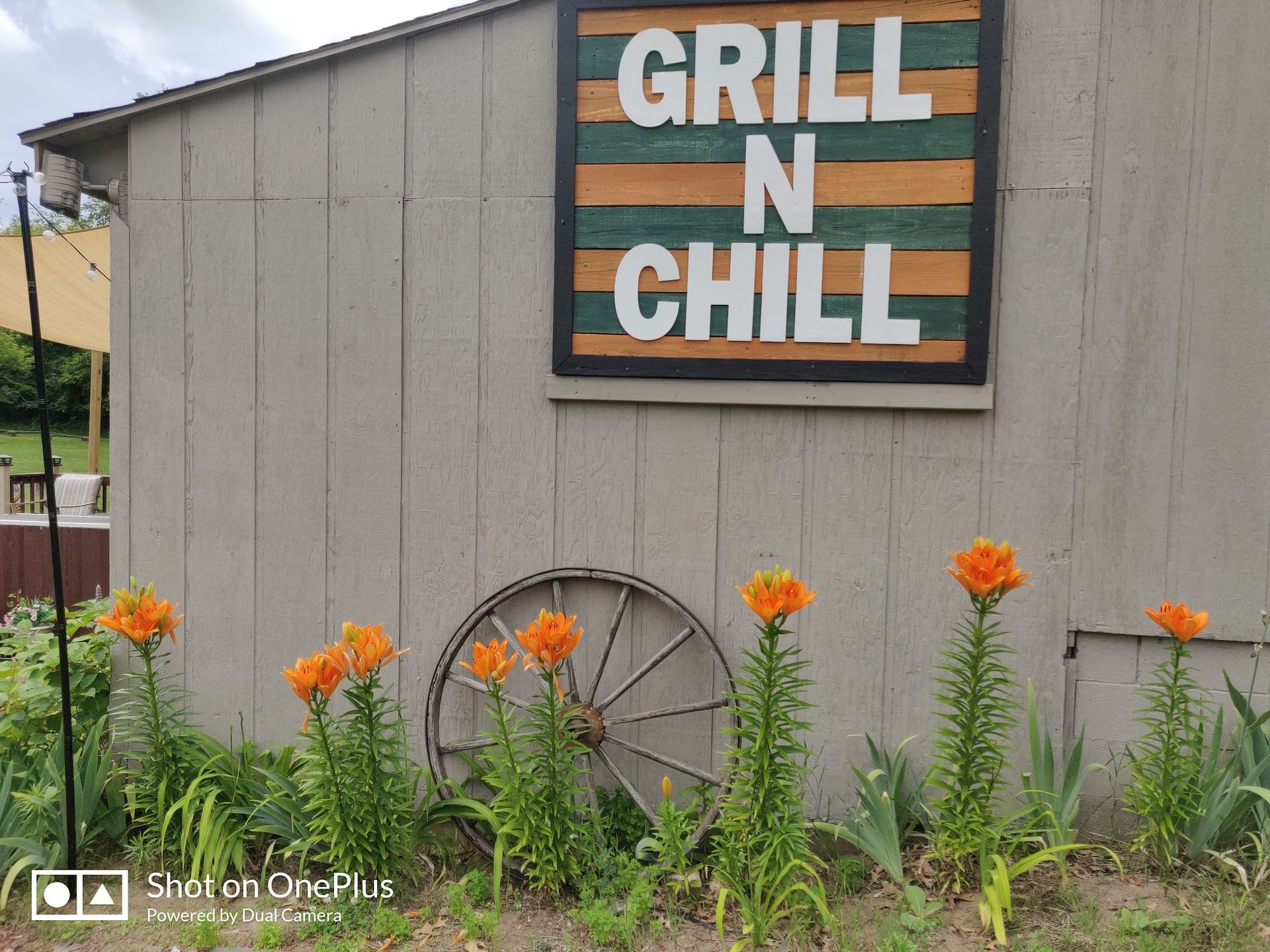 “GRILL N CHILL” sign above orange flowers beside a gray building