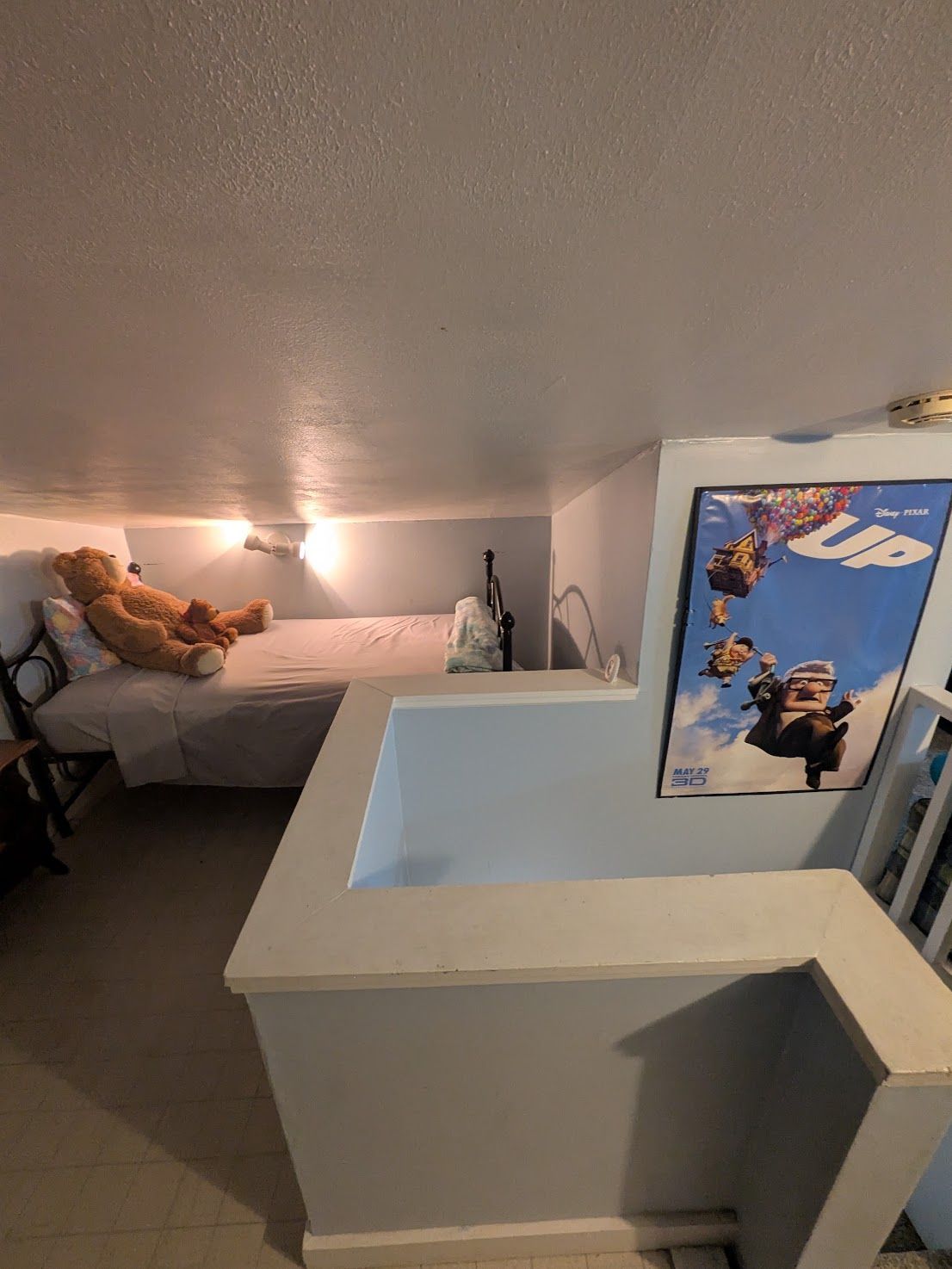 Loft bedroom with a bed, ceiling light, and a blue surf-themed wall panel near the stairs