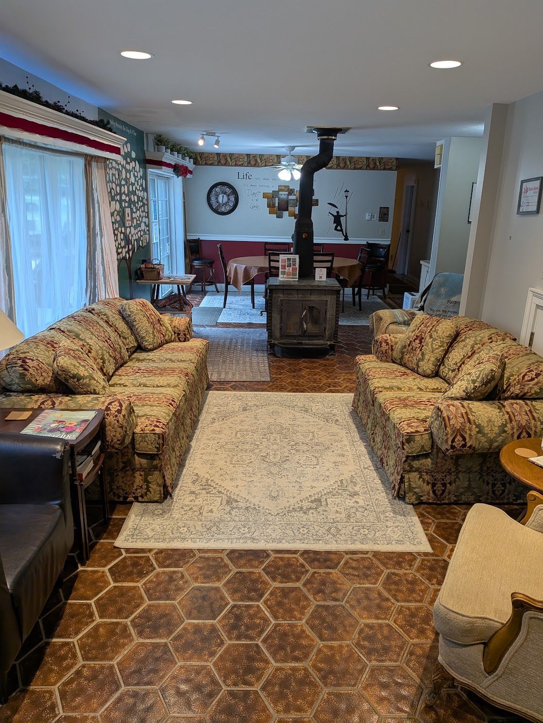Living room with patterned sofas, brick hearth, rug, and dining area in the background