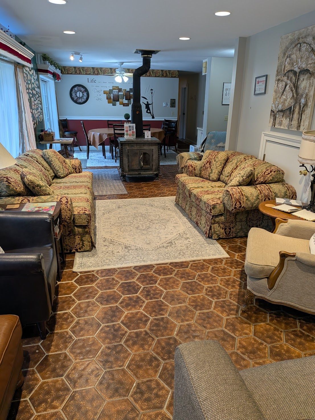 Living room with patterned sofas, rug, and wood stove in a bright, open interior