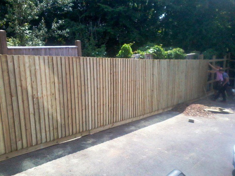 A wooden fence is being built in a driveway
