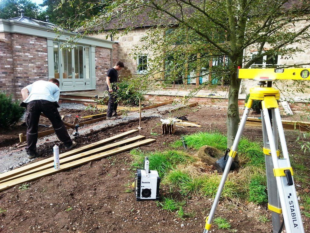A group of men are working in a garden in front of a house.