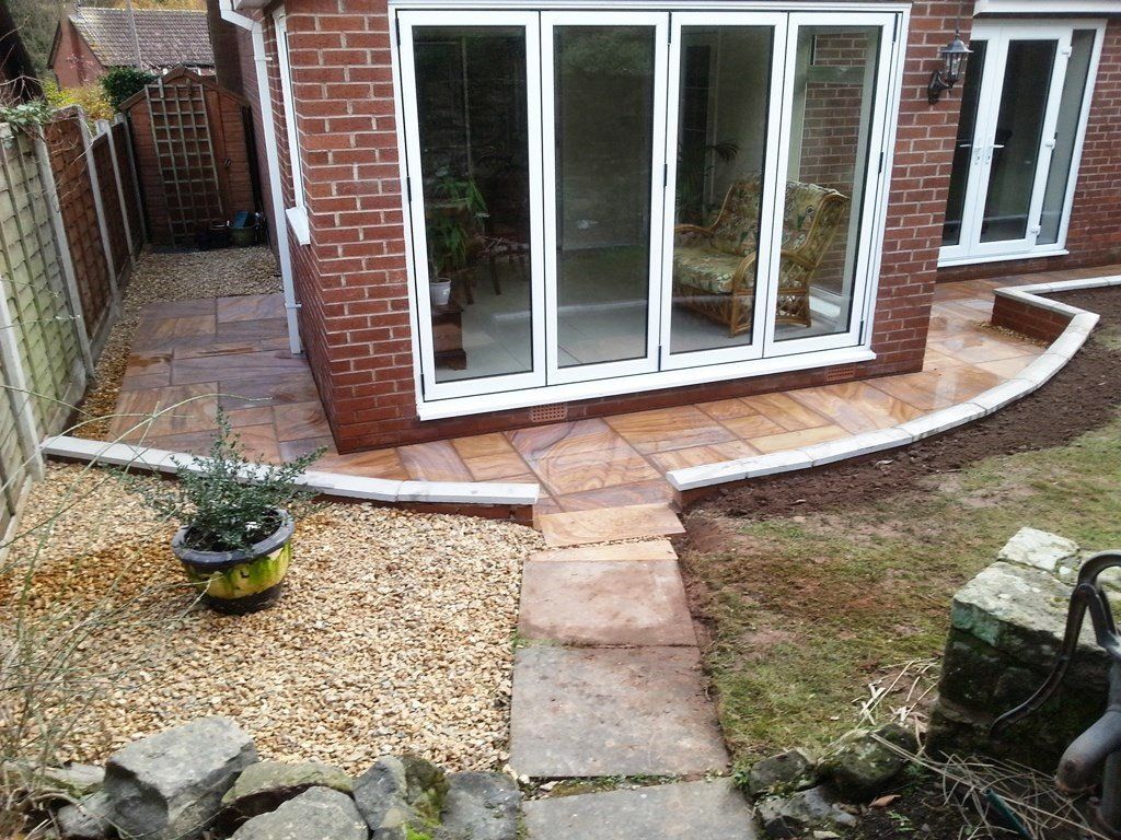 A brick house with a patio and a walkway leading to it.