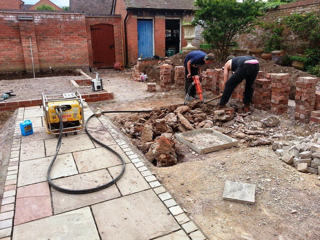 A man is digging a hole in the ground in a backyard.