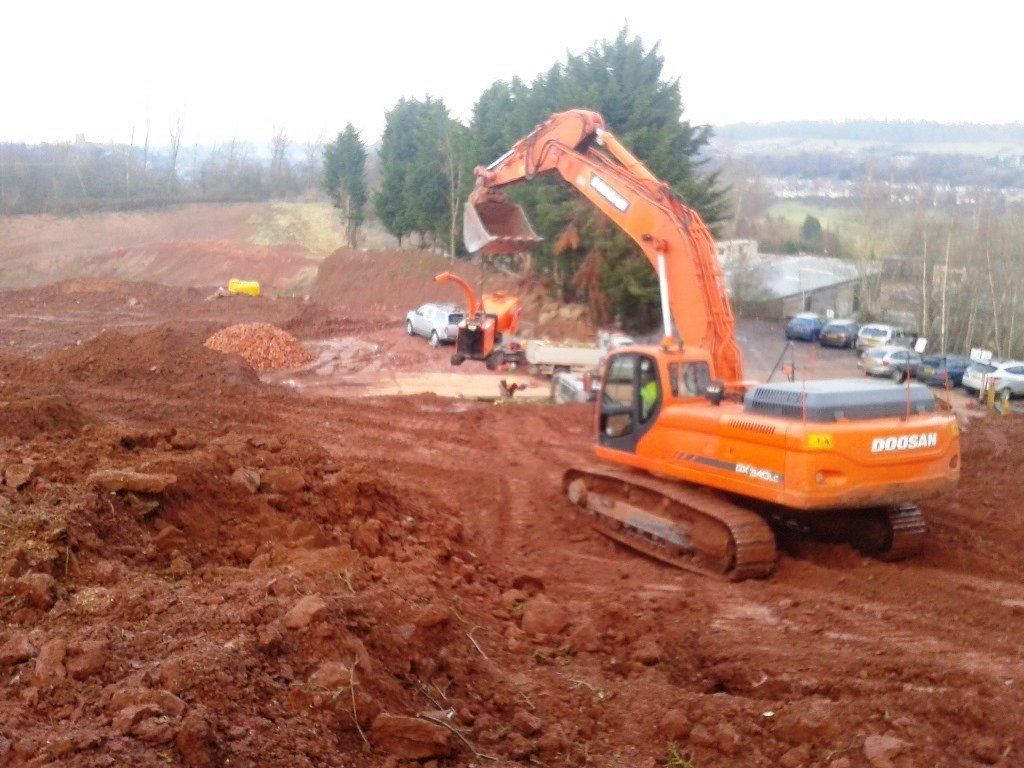 A large orange excavator is driving through a dirt field.