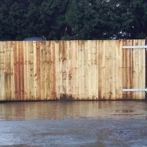 A wooden fence is sitting in the middle of a wet parking lot.