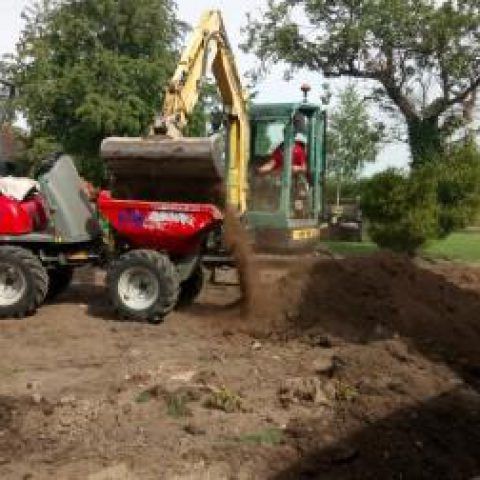 A bulldozer is loading dirt into a dump truck.