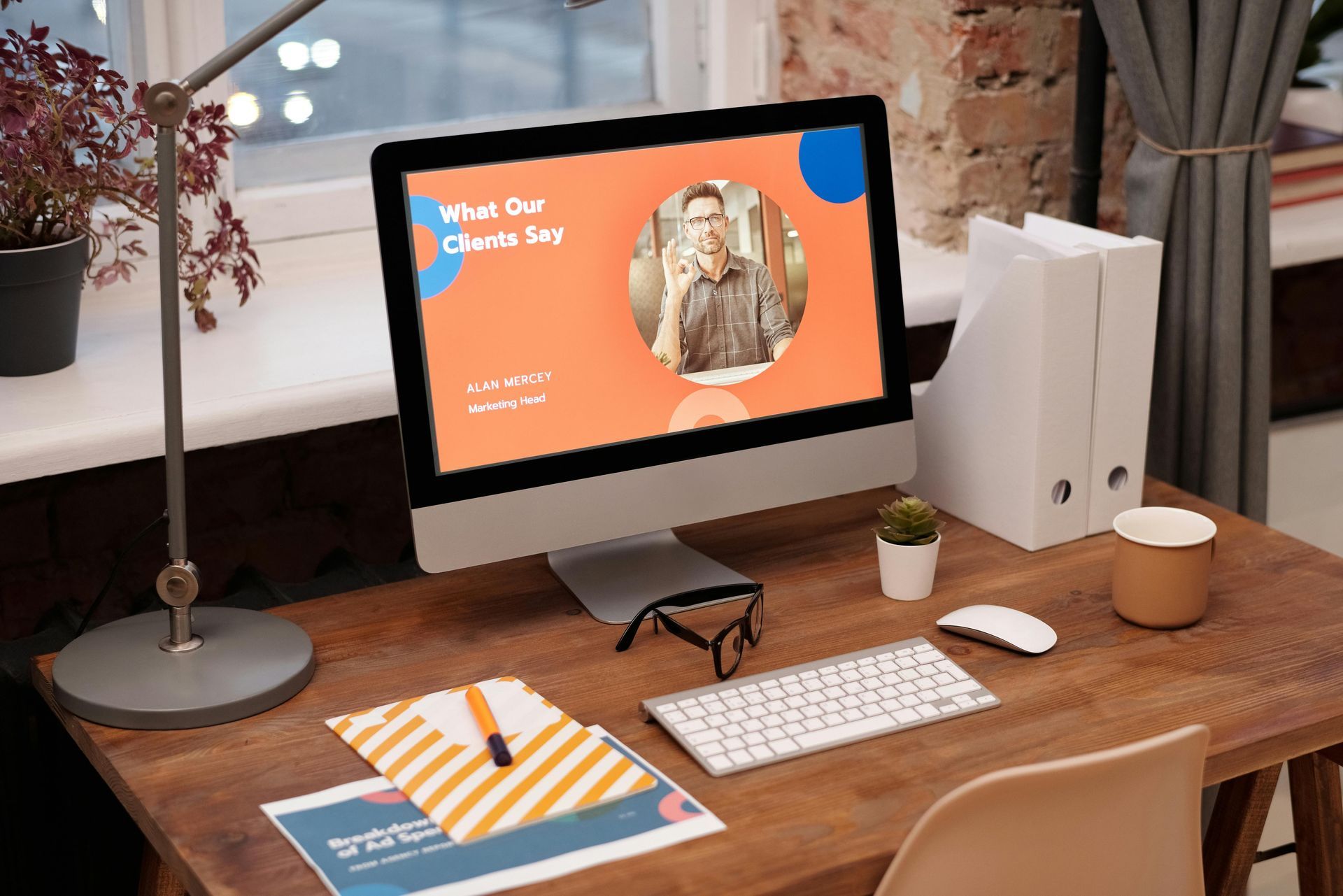 Desktop computer on a wooden desk displays presentation with photo, blue and orange accents.
