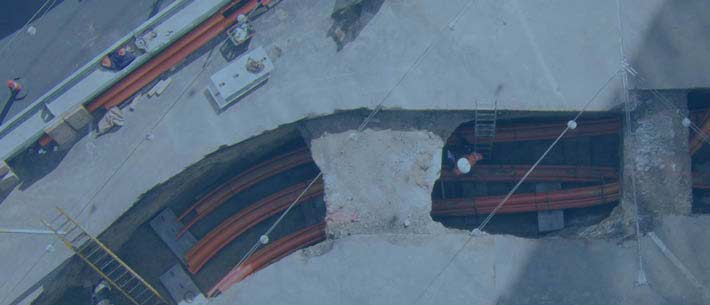 Aerial view of construction site with trench, pipes, and scaffolding.
