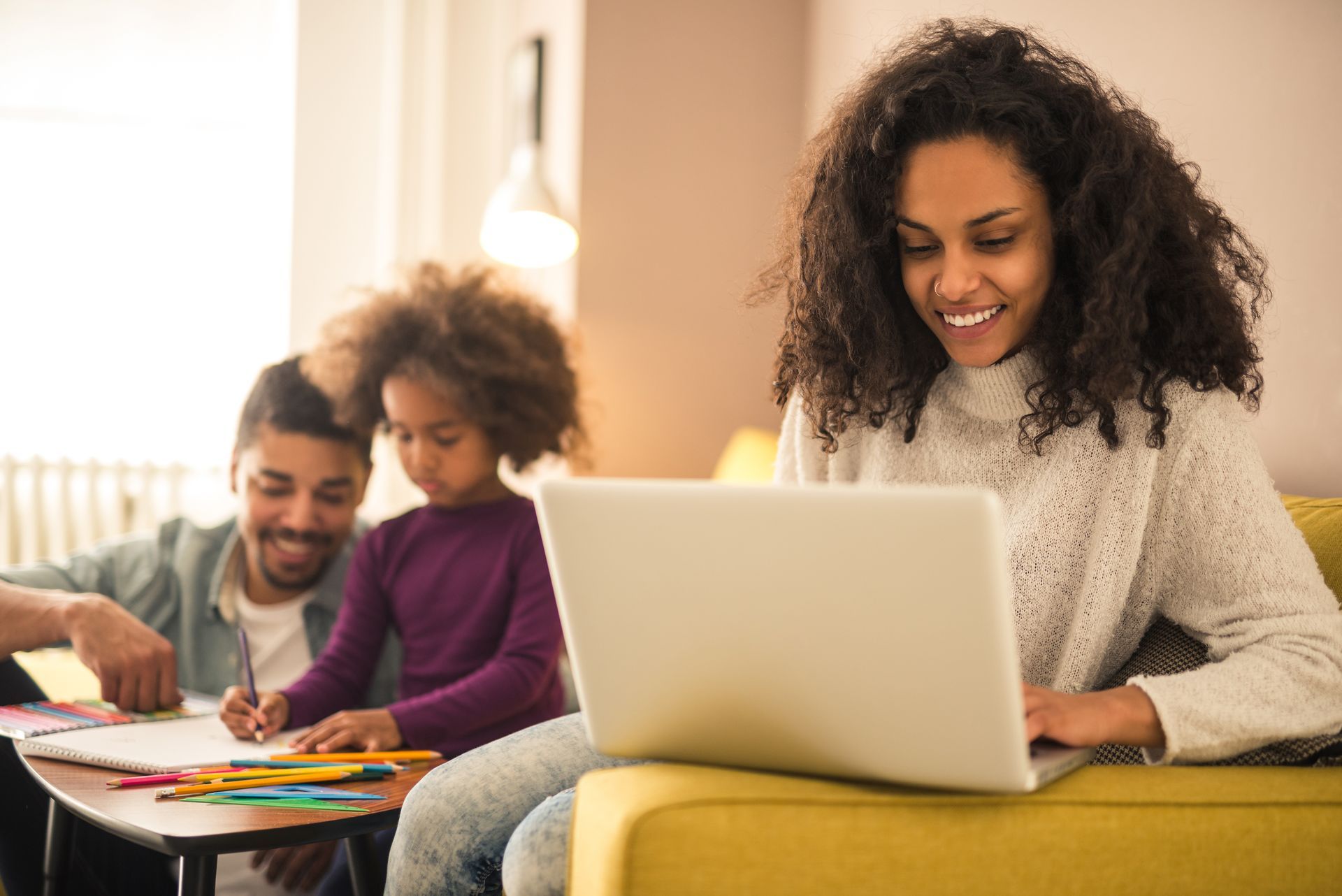mother on her computer with her family in the background