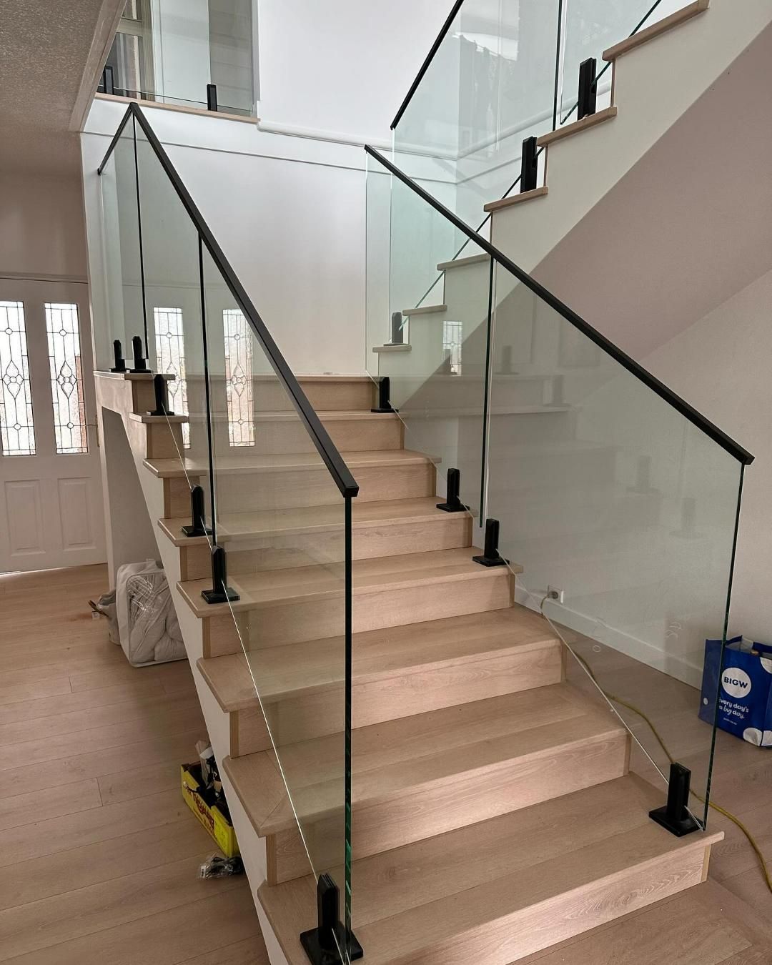A Staircase with A Glass Railing and Wooden Steps — Optimum Aluminium Fabrication in Dapto, NSW