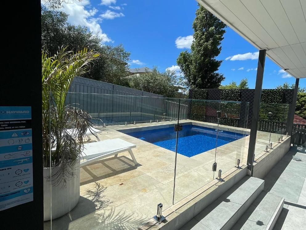 A Large Swimming Pool Is Surrounded by A Glass Fence — Optimum Aluminium Fabrication in Barrack Heights, NSW