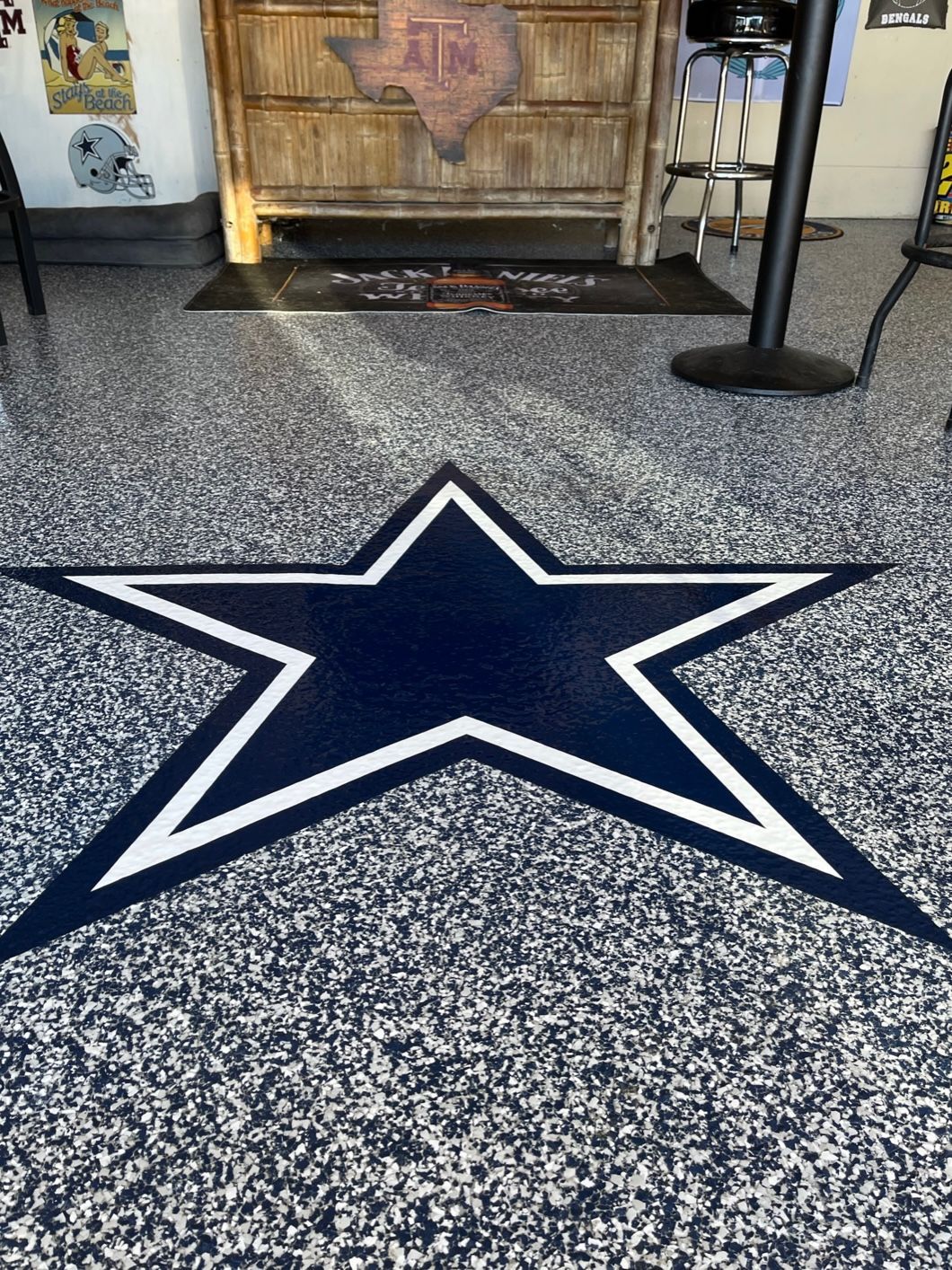 Dallas Cowboys star logo on a speckled epoxy floor. Dark blue star with white border.