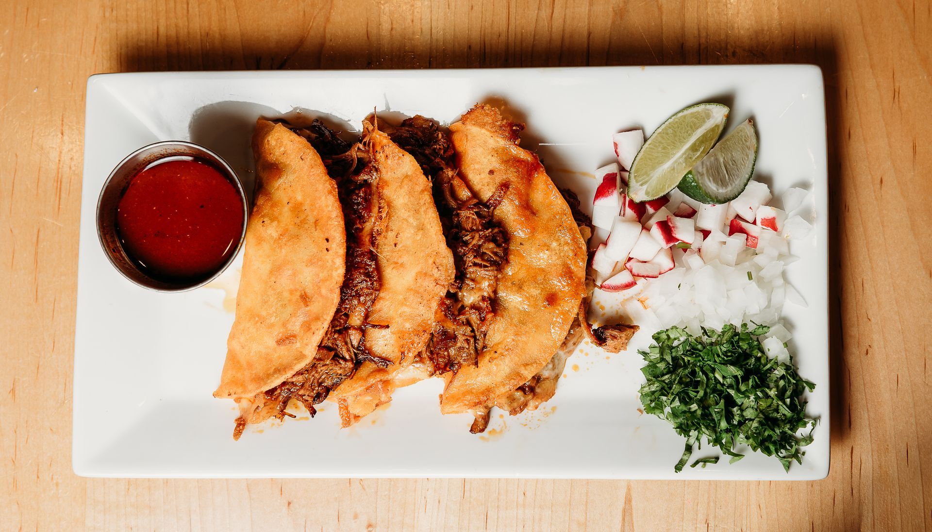 There are many different types of tacos and salsas on the table.
