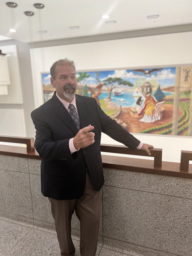 A man in a suit and tie is standing in front of a painting