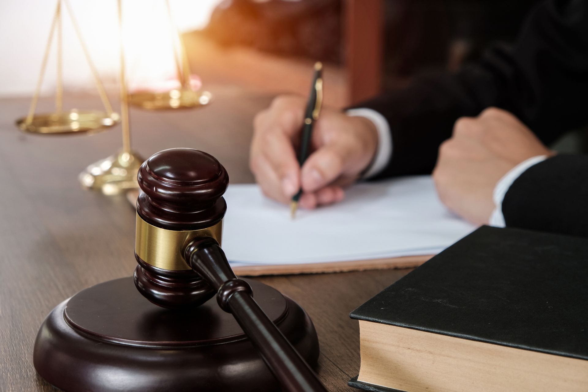 A judge is writing on a piece of paper next to a gavel.