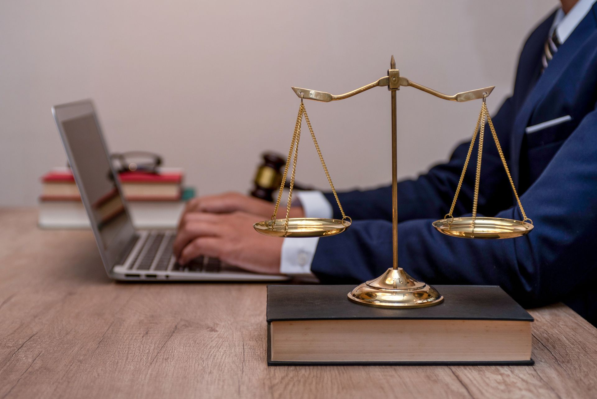 A lawyer is typing on a laptop next to a scale of justice.