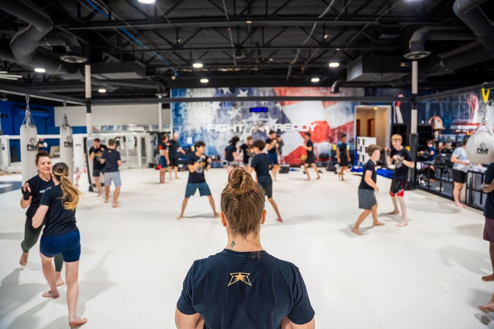 Martial arts class practicing in a bright gym with mats and mirrors