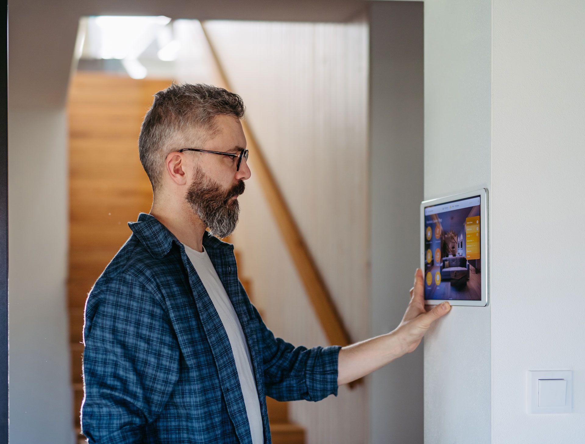 A man is using a tablet to control a smart home.