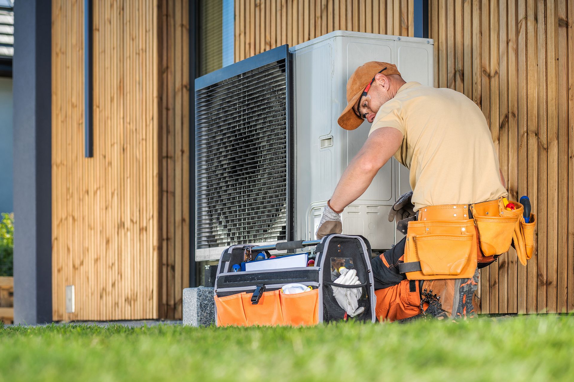 A man is working on a heat pump outside of a house.
