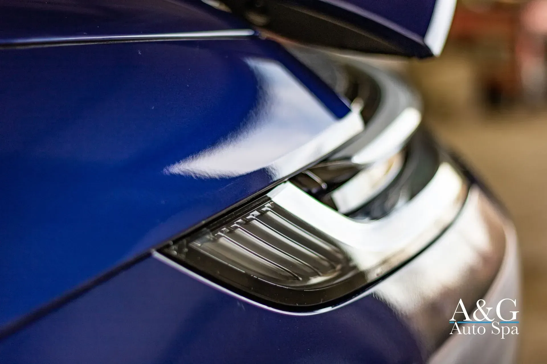 A close up of the headlight of a blue car.