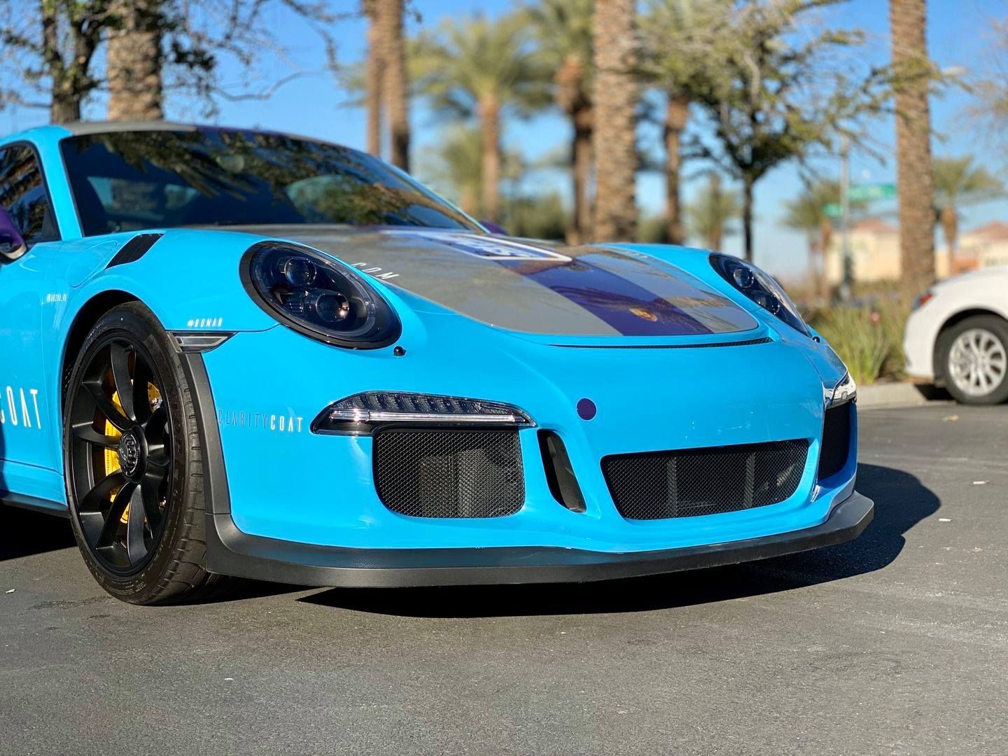 A blue porsche 911 gt3 rs is parked on the side of the road.