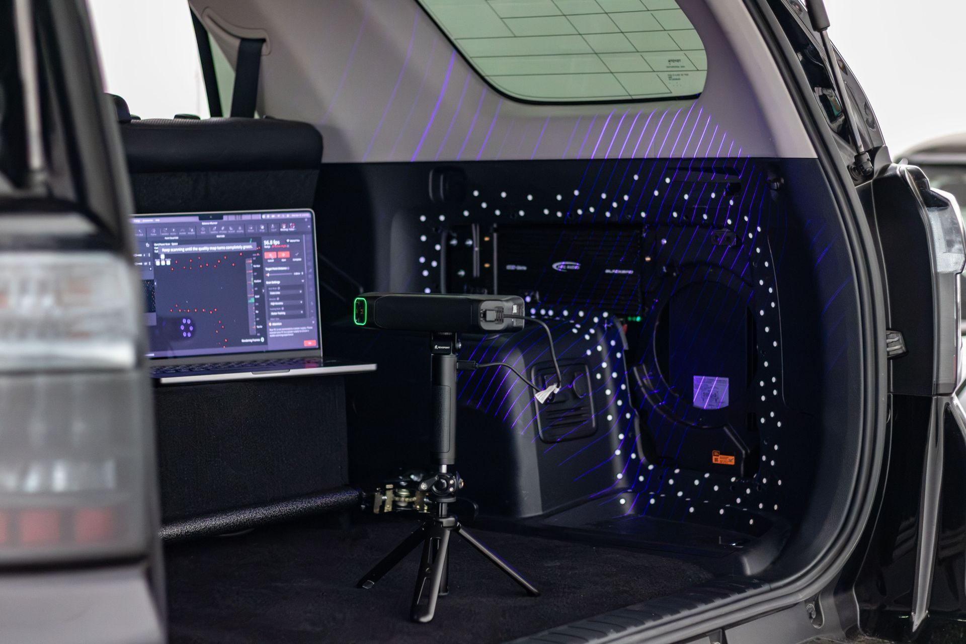 Laptop and tripod camera setup in a car trunk, lit with purple LEDs and a starry interior panel