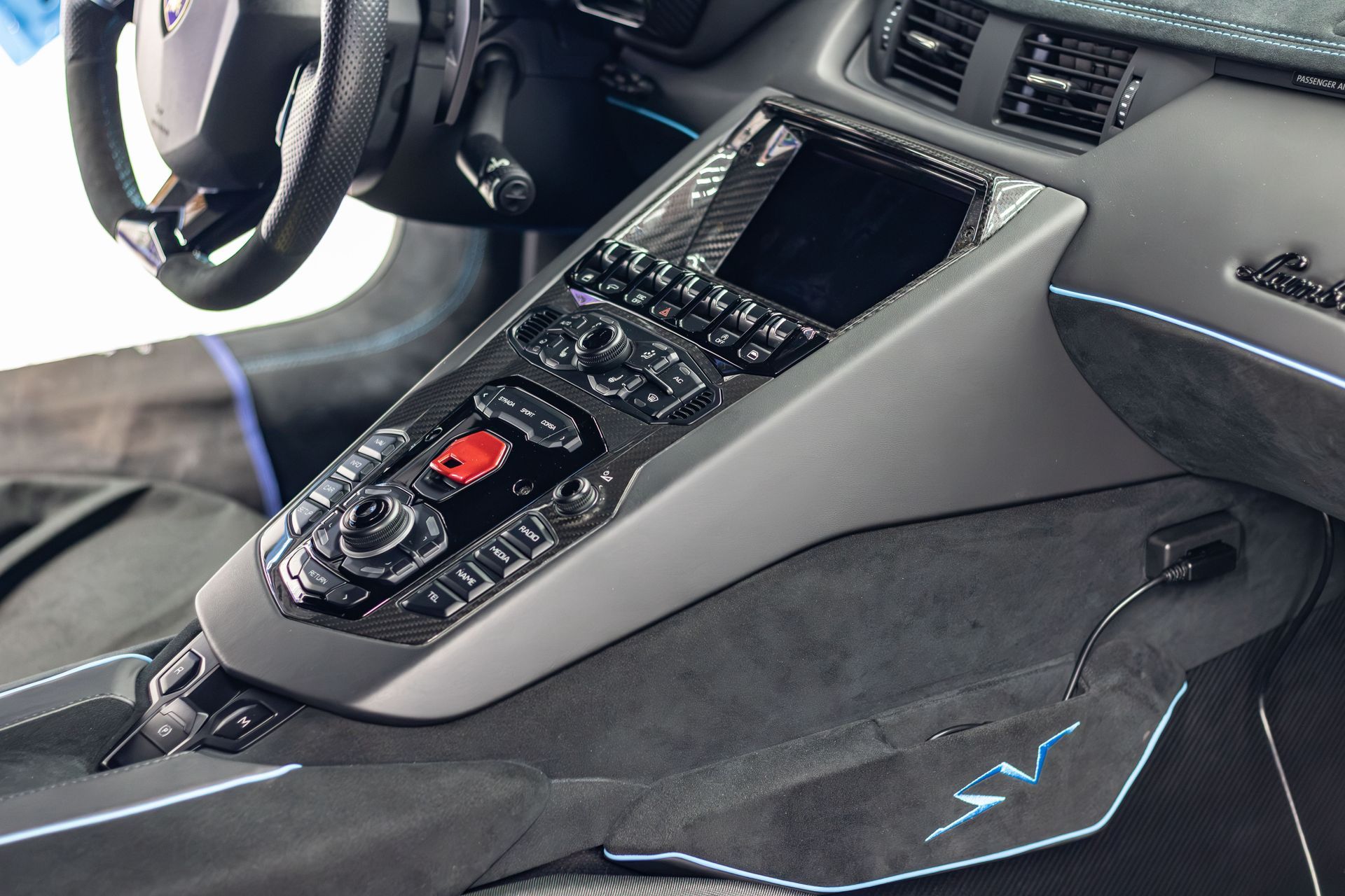 Luxury car interior with a center console, touchscreen, and black seats with blue accent lighting