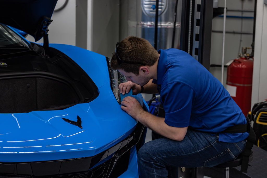 A man is working on a blue sports car in a garage.