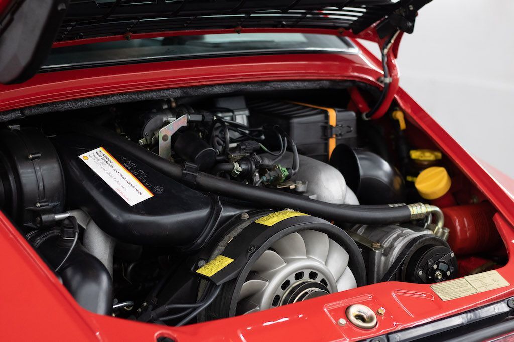 A close up of a red car engine with the hood open.