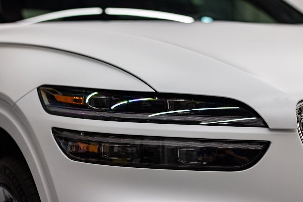 A close up of the headlights of a white car.