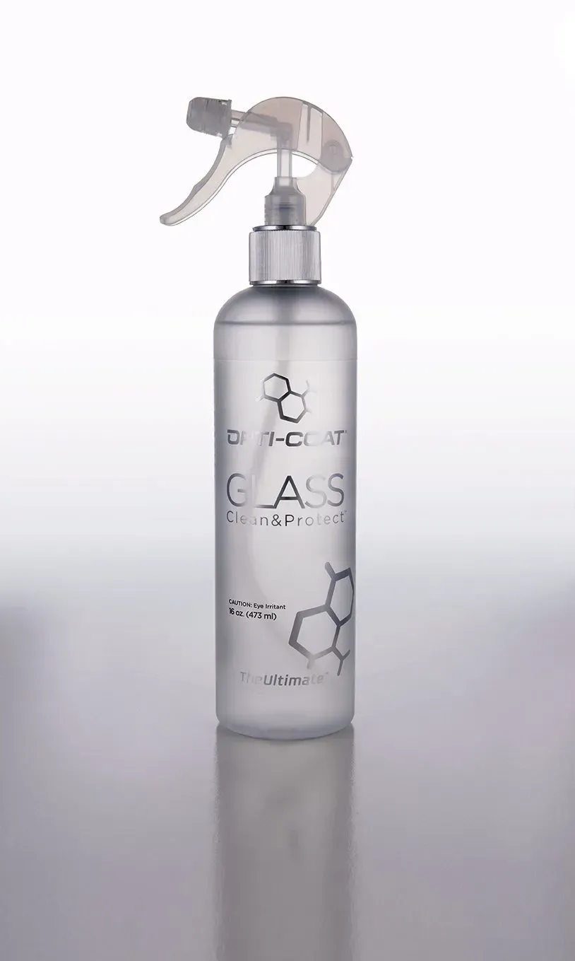 A bottle of glass cleaner with a sprayer on a white surface.