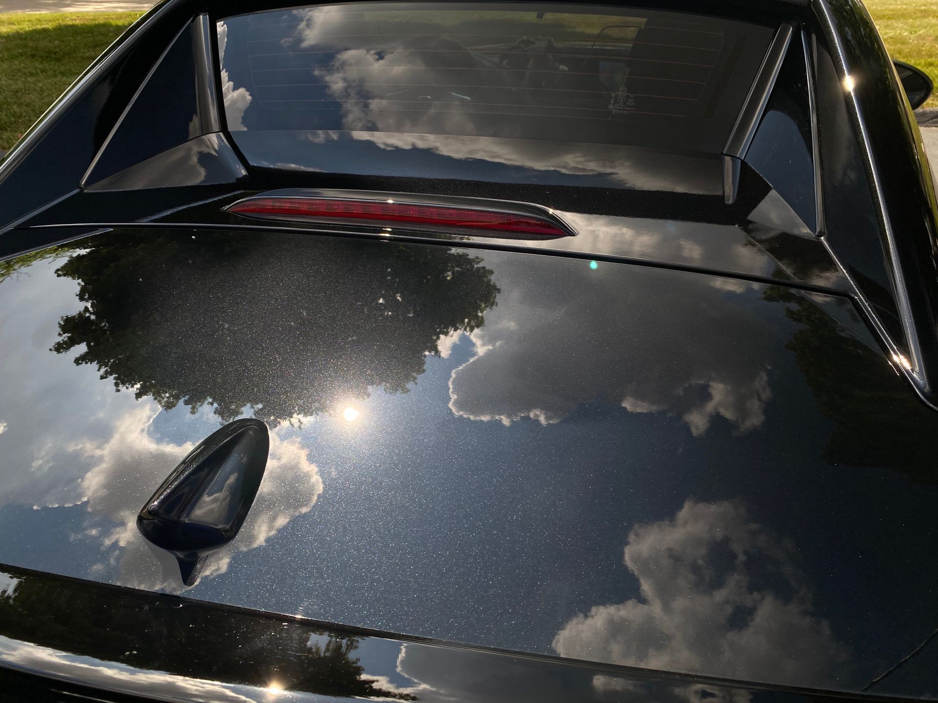 A black car with a reflection of clouds in the hood