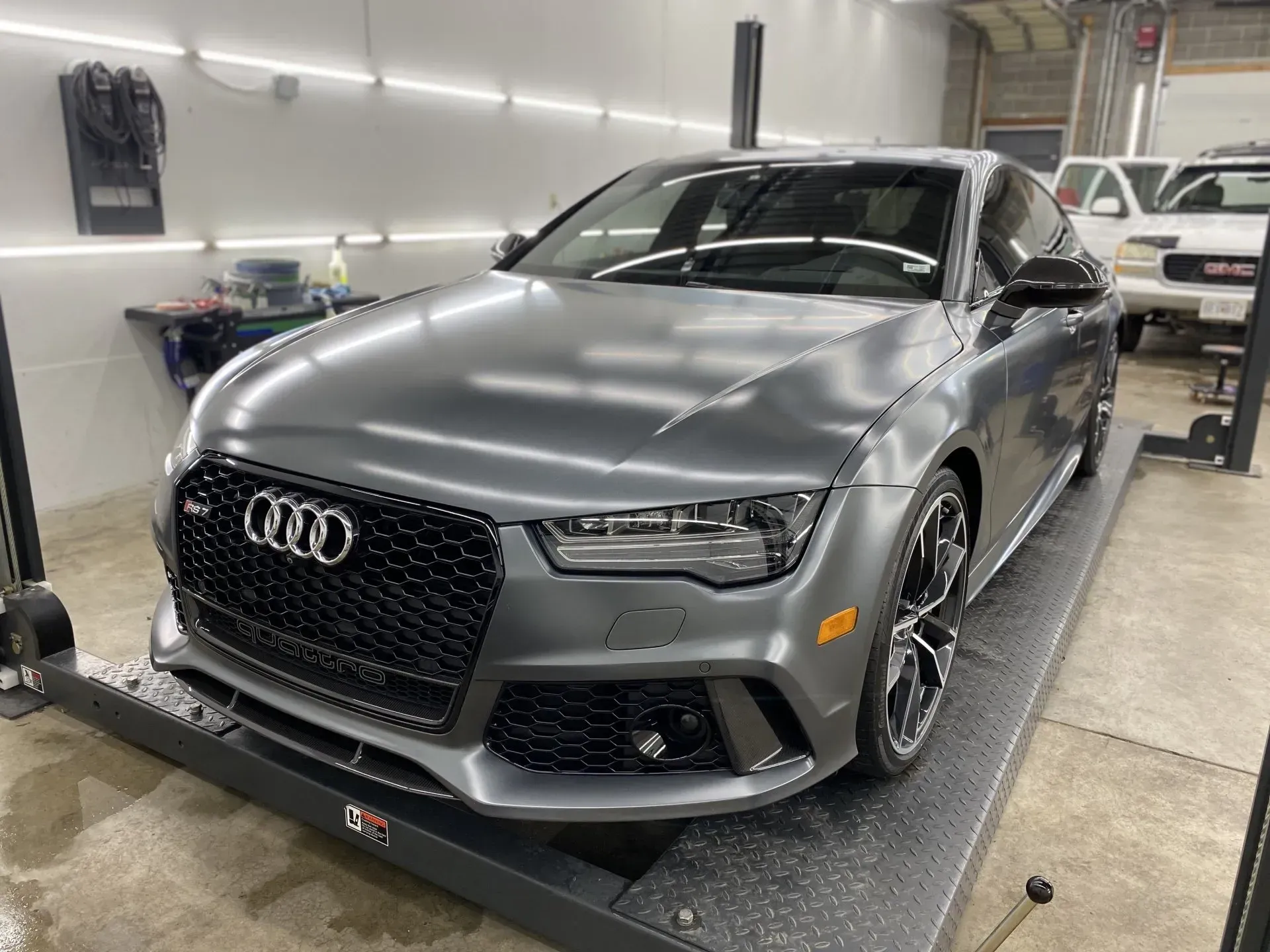 A gray audi a7 rs is parked on a lift in a garage.